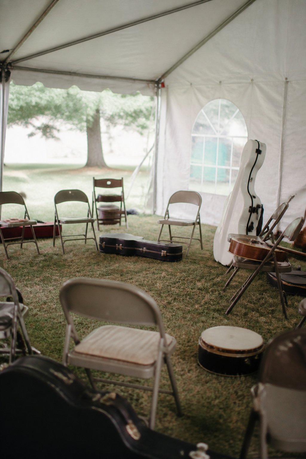 A ring of folding chairs and instrument cases in a campsite marquee before a jam starts
